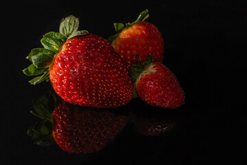 Three Strawberries on a black plastic