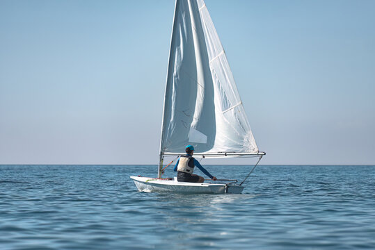 Young sportsman sailing alone in the sea on a dinghy