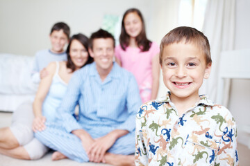 Bedroom, pajamas and portrait of happy boy with family blur in home for support, love or wellness. Weekend, mother or dad with toddler, children or growth for bonding together with parents in morning