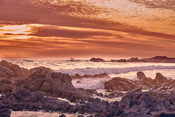 Scenery, rocks and water in beach, sunset and location of environment, waves and summer in destination. Sea, stones and tropical in ocean, outdoor and adventure in morning, paradise and California