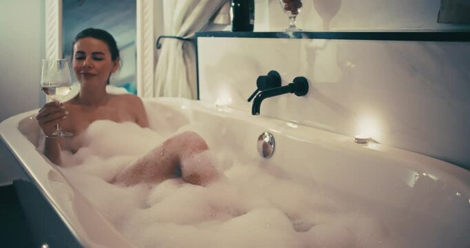 Beautiful Woman Bathing with a Glass of Wine in a Cozy Candlelit Bathroom, Relaxation and Romance After a Long Day. High quality 4k footage