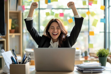 A senior Hispanic businesswoman celebrates with a joyful smile in her brightly lit office. She gazes at a laptop showing e-commerce growth and digital sales success, highlighting her accomplishments
