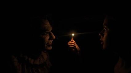 Obraz premium Young woman standing in darkness at attic in ruined house, lights up match sees mad man killer dressed as clown and screams. Halloween thriller concept.
