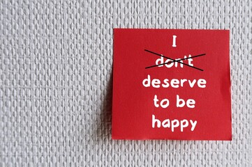 Red note stick on wallpaper with handwritten text - I don't deserve to be happy - change to I...