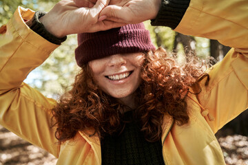 Playful Woman Covering Her Eyes with a Hat in the Park
