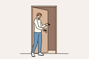Fototapeta premium Man says welcome standing near door and shows inviting gesture when friends come to visit. Guy demonstrating welcome sign with palm, showing friendly and hospitable character traits