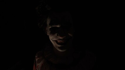 Crazy creepy killer man dressed as clown with makeup at attic in ruined house looks at camera, talking, smiling going crazy. Halloween thriller concept.