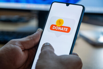 Close-up of “Donate” message on smartphone screen. Online donation concept. Office background....