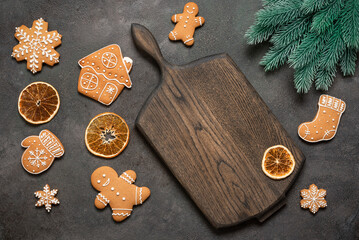 Christmas culinary background with gingerbread cookies and empty wooden board, fir branch and dried orange slices, top view, flat lay.