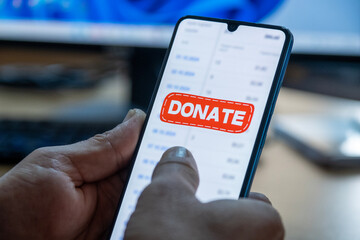 Close-up of “Donate” message on smartphone screen. Online donation concept. Office background....