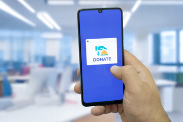 Close-up of “Donate” message on smartphone screen. Online donation concept. Office background. Donate message. 
