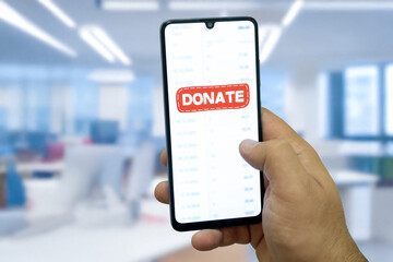 Close-up of “Donate” message on smartphone screen. Online donation concept. Office background. Donate message. 