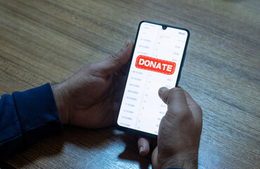 Close-up of “Donate” message on smartphone screen. Online donation concept. Office background....