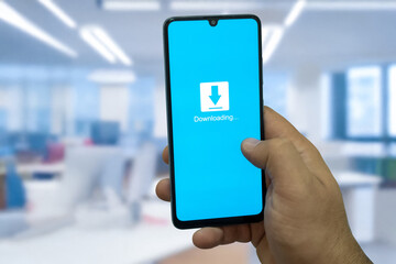 Close-up of “Download” message on smartphone screen. Online file download concept. Office background. Download message. 