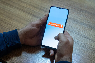 Close-up of “Download” message on smartphone screen. Online file download concept. Office background. Download message. 