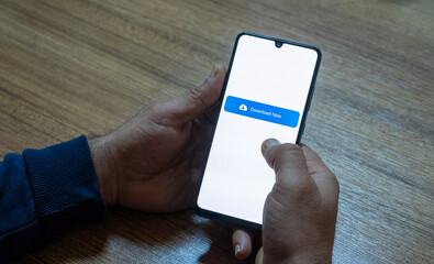 Close-up of “Download” message on smartphone screen. Online file download concept. Office background. Download message. 