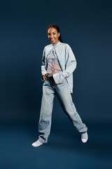 Fototapeta premium A confident young woman models an eye catching outfit against a bold background, exuding charisma.