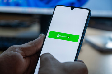 Close-up of “Download” message on smartphone screen. Online file download concept. Office background. Download message. 
