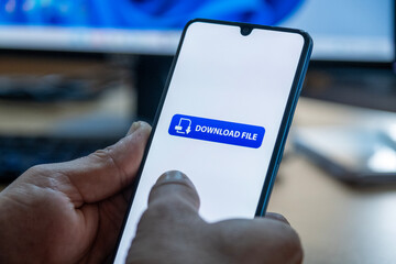 Close-up of “Download” message on smartphone screen. Online file download concept. Office background. Download message. 