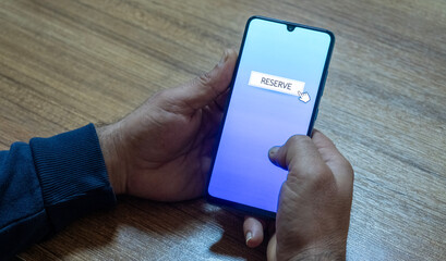 “Reserved” message on close-up smartphone screen. Online reservation. Office background. Hotel, vacation or event booking message. 