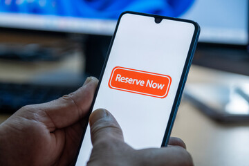 “Reserved” message on close-up smartphone screen. Online reservation. Office background. Hotel, vacation or event booking message. 