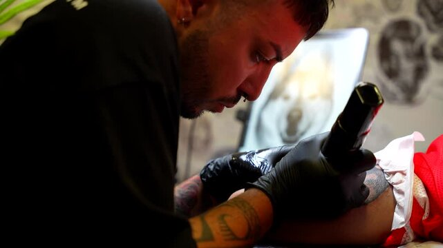 Tattoo artist applies vaseline on the skin of his client and continue painting with ink on her arm