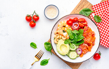 Salad bowl with salmon, shrimps, avocado, spinach, vegetables, sesame and cashew nuts for keto diet. White background, top view