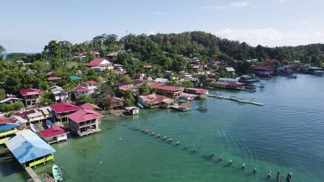 Aerial establishing shot of picturesque stilt house village by turquoise water, Bastimentos Island, Panama