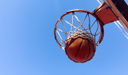 Basketball scoring a basket as it goes through the hoop and making a swish in the net