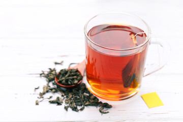 Cup of tea with tea bag and spoon on white wooden table