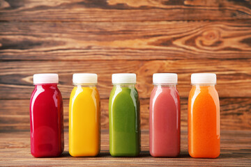 Fresh smoothies in plastic bottles on brown wooden background