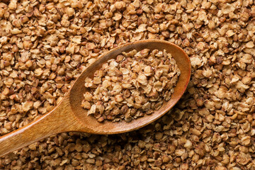 Buckwheat flakes in a wooden spoon background. Top view