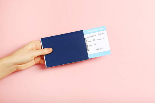Hand holding boarding pass and passport on pink background