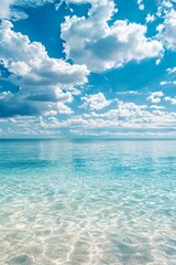 Obraz premium A serene scene of the clear blue sky and turquoise ocean, with fluffy white clouds in the background. The water is crystal clear, reflecting the vibrant colors of the sky above it. 
