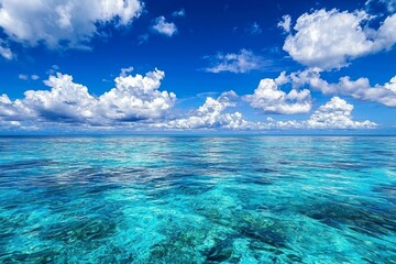 A serene scene of the clear blue sky and turquoise ocean, with fluffy white clouds in the background. The water is crystal clear, reflecting the vibrant colors of the sky above it. 