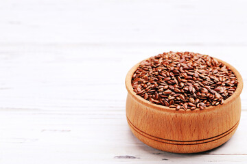 Flax seeds in bowl on white wooden background