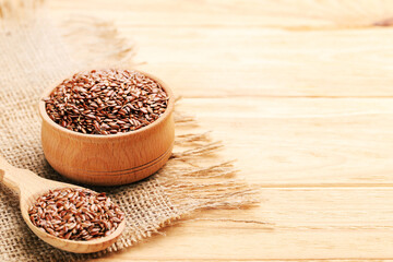 Flax seeds in scoop and bowl on brown wooden background