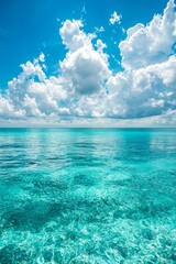 Obraz premium A serene scene of the clear blue sky and turquoise ocean, with fluffy white clouds in the background. The water is crystal clear, reflecting the vibrant colors of the sky above it. 