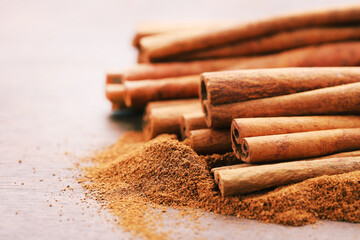 Cinnamon powder with sticks on brown wooden background