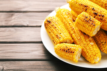 Fresh grilled corn in plate on wooden background