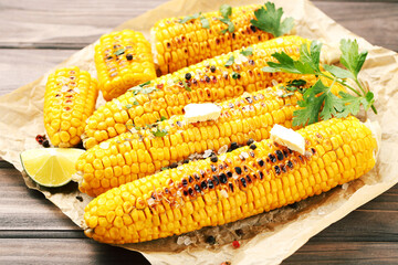 Tasty grilled corn with green parsley, spices and butter on wooden table