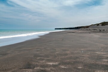 Serene black sand beach with gentle waves.