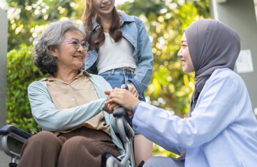 Female doctor in hijab comforting elderly woman in wheelchair with caregiver showing compassion and...