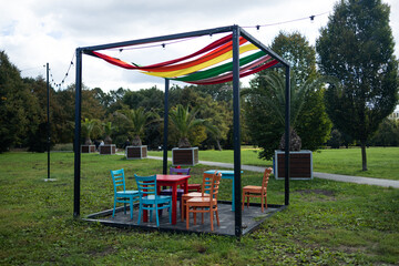 Beautiful modern gazebo with observation chairs and a table for relaxing in a city summer park