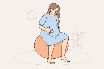 Pregnant woman feels contractions and labor is approaching, sits on fitness ball