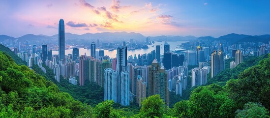Naklejka premium Breathtaking sunset view over Hong Kong skyline with lush green hills in the foreground.