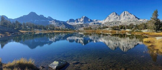 Fototapeta premium A tranquil mountain lake with a clear reflection of the snow-capped peaks in the still water.