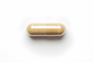 A close-up image of a single beige capsule pill isolated on a white background.