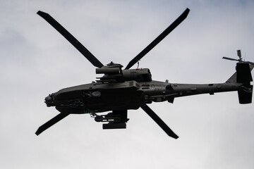 Fototapeta premium close-up of a British army Boeing Apache Attack helicopter gunship AH64E AH-64E ArmyAirCorp banking hard in low level overhead flight