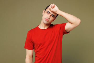 Young sad middle eastern man he wearing red t-shirt casual clothes put hand on forehead suffer from...